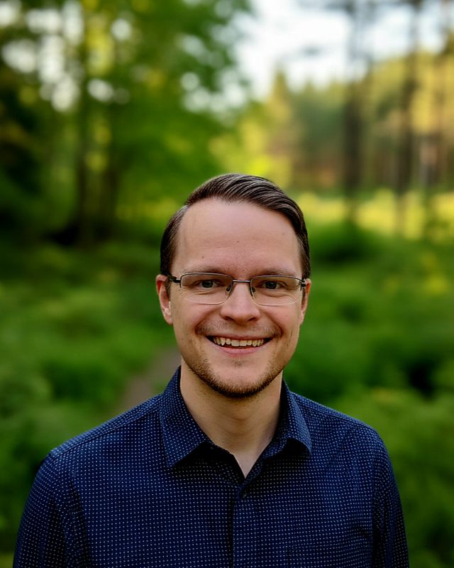 Joel Rivers outdoors in a green forest, smiling